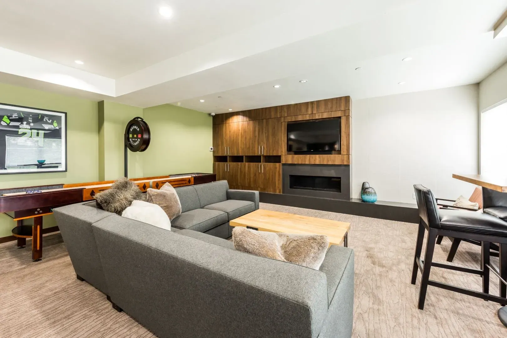 Community lounge area with shuffleboard, foosball, fireplace, and seating.