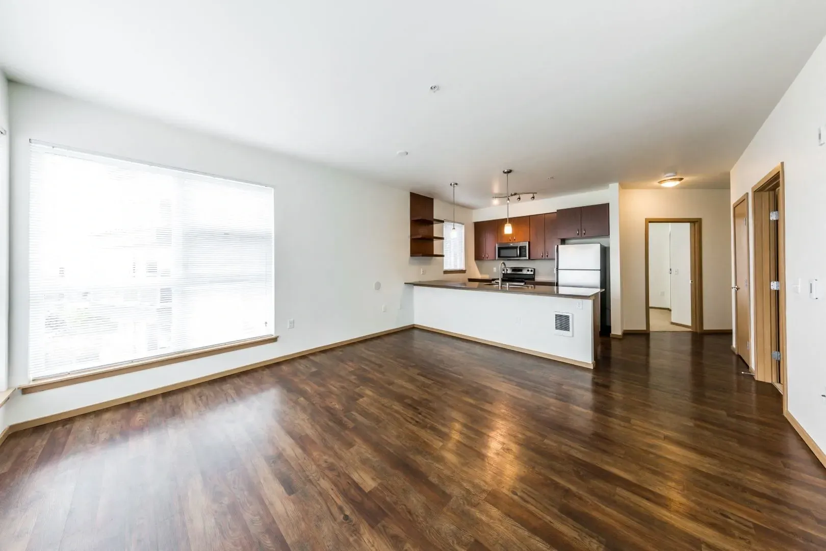 Spacious living area with large window and open-concept kitchen with stainless steel appliances.