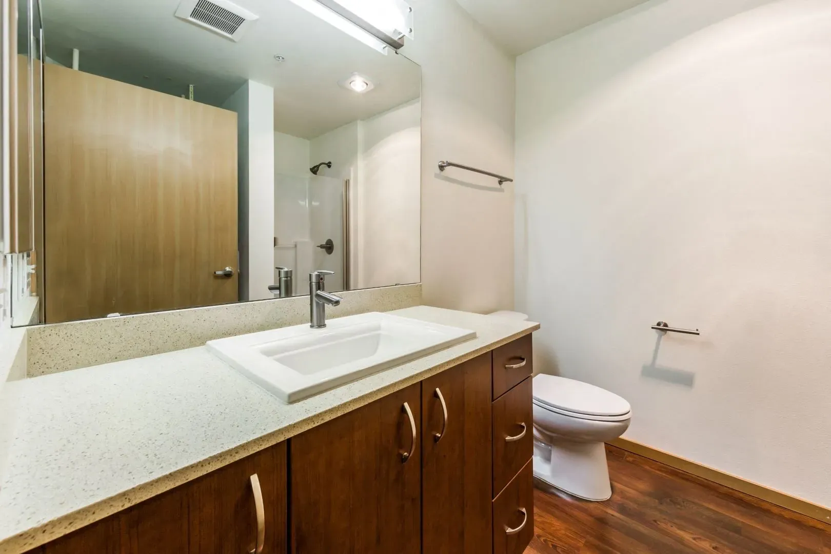 Modern bathroom vanity with sink, wooden cabinets, and toilet.
