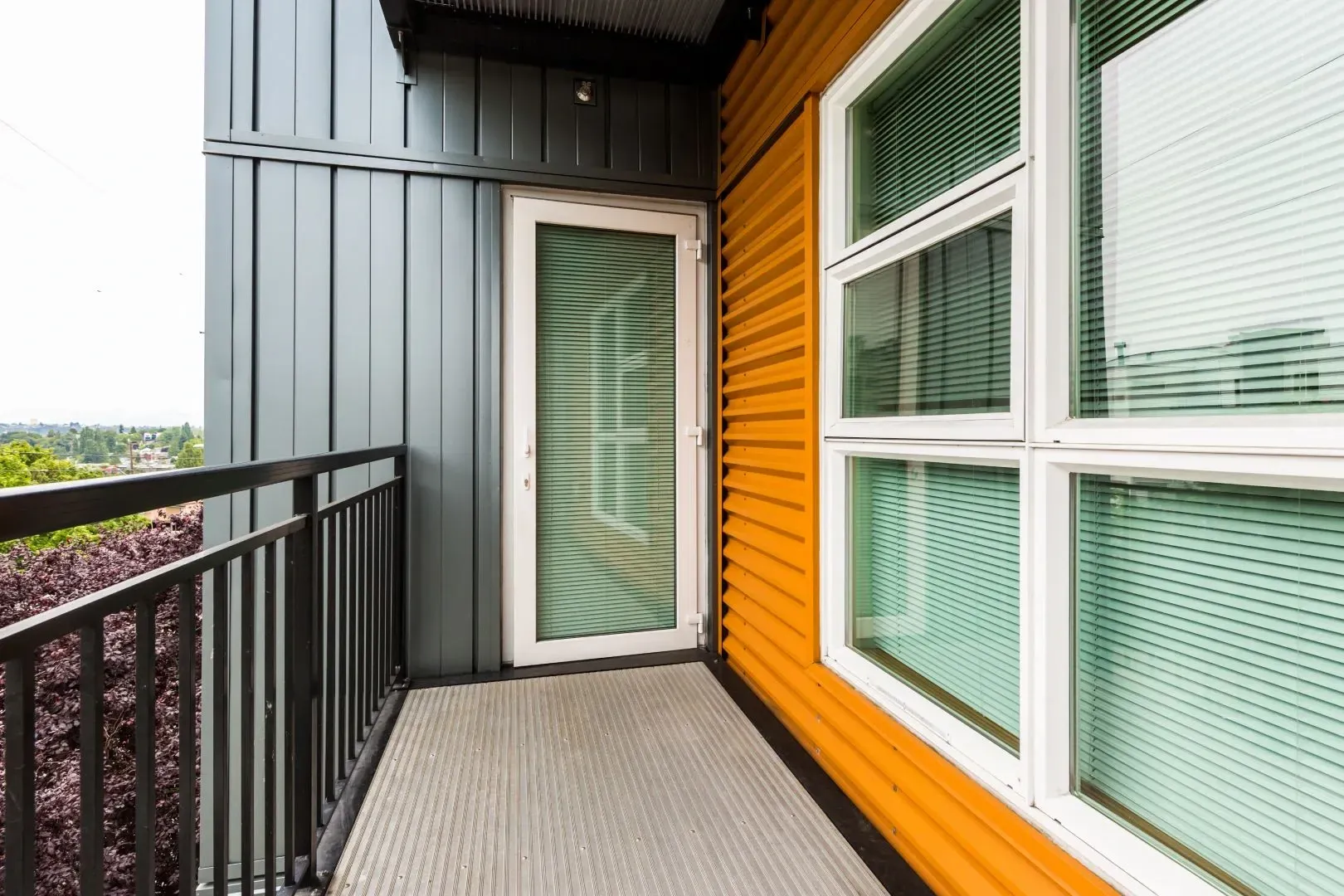 Balcony with grey siding and orange corrugated metal exterior.