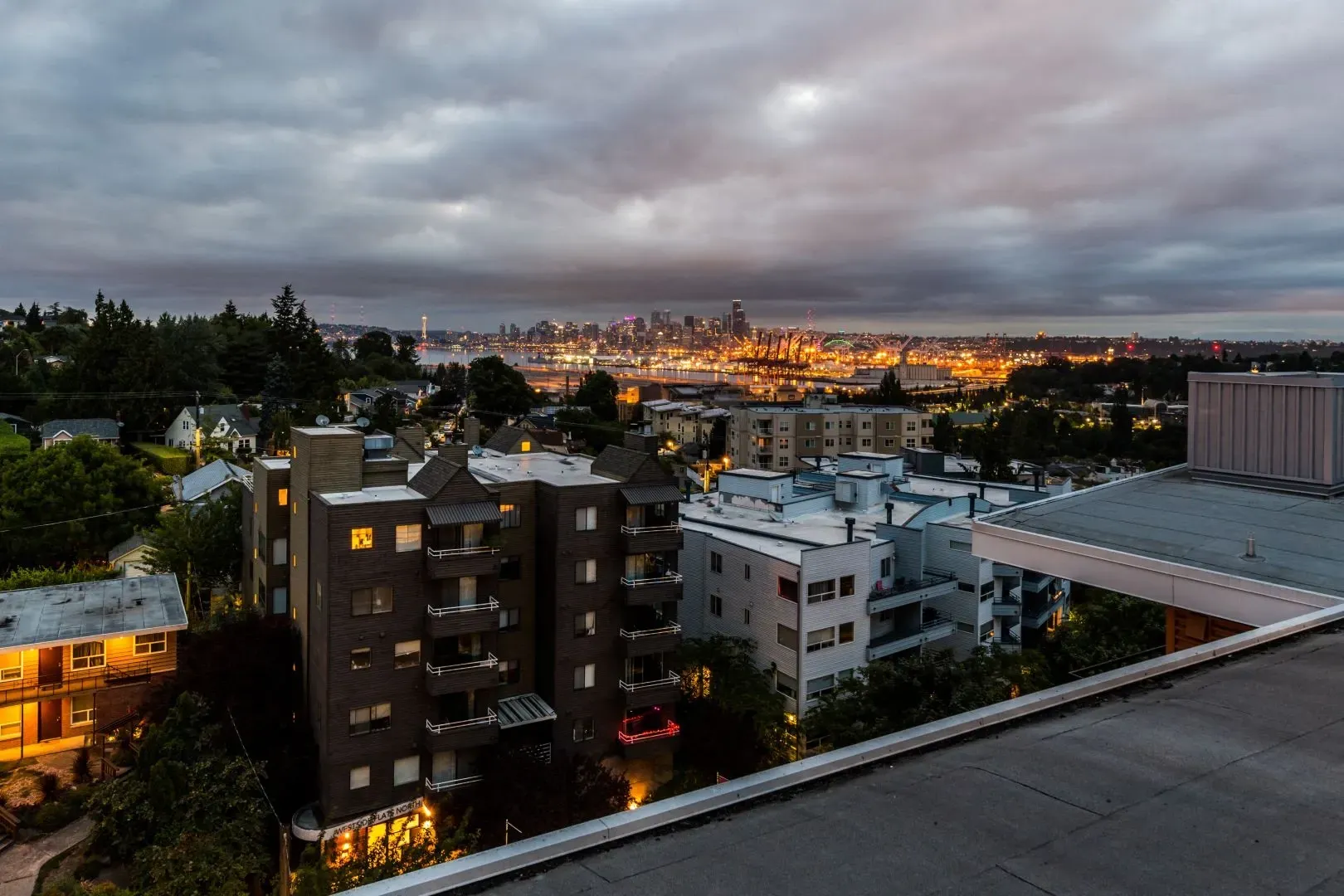 Apartment buildings with a city skyline in the background at dusk.