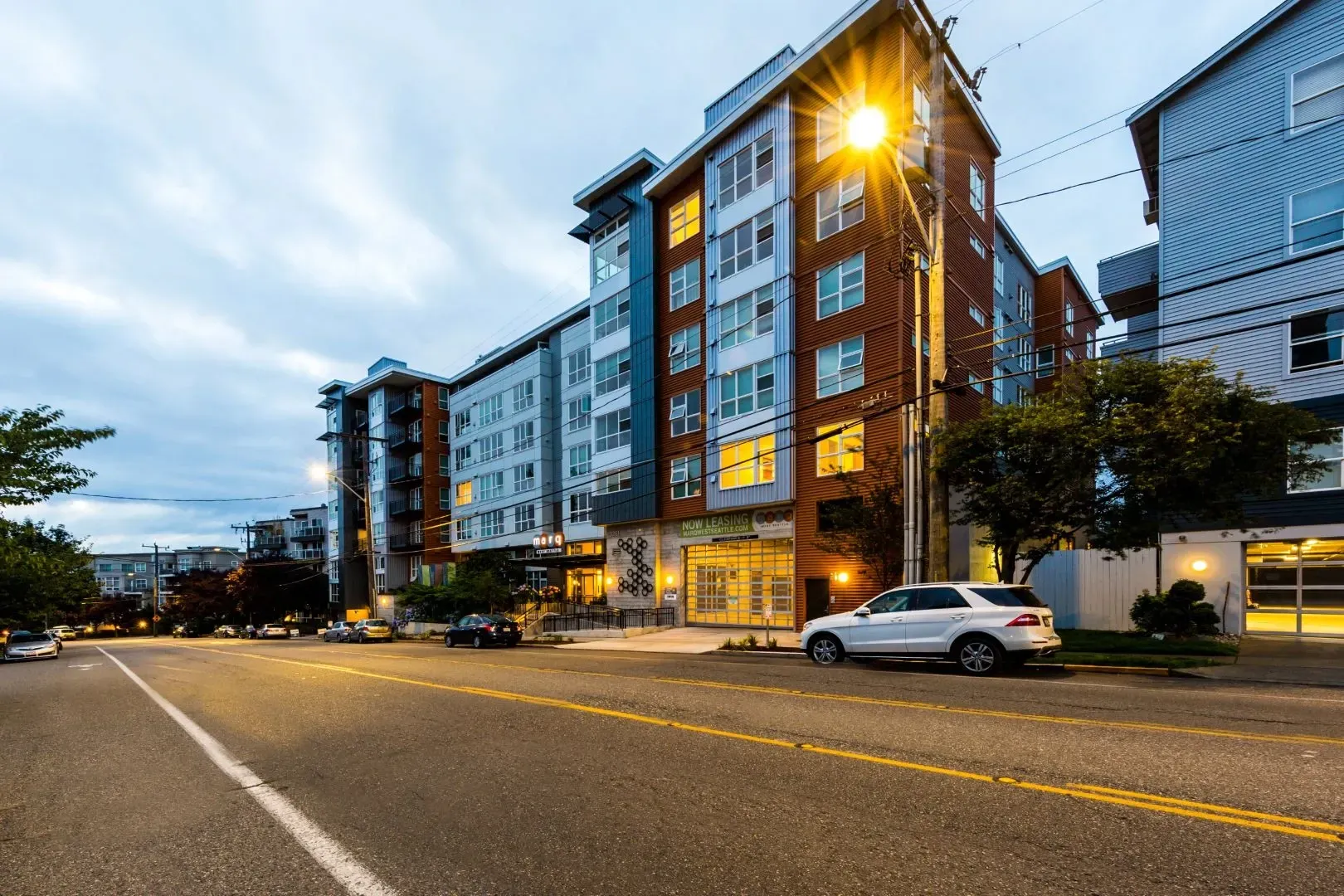 Modern apartment building exterior with street and cars.
