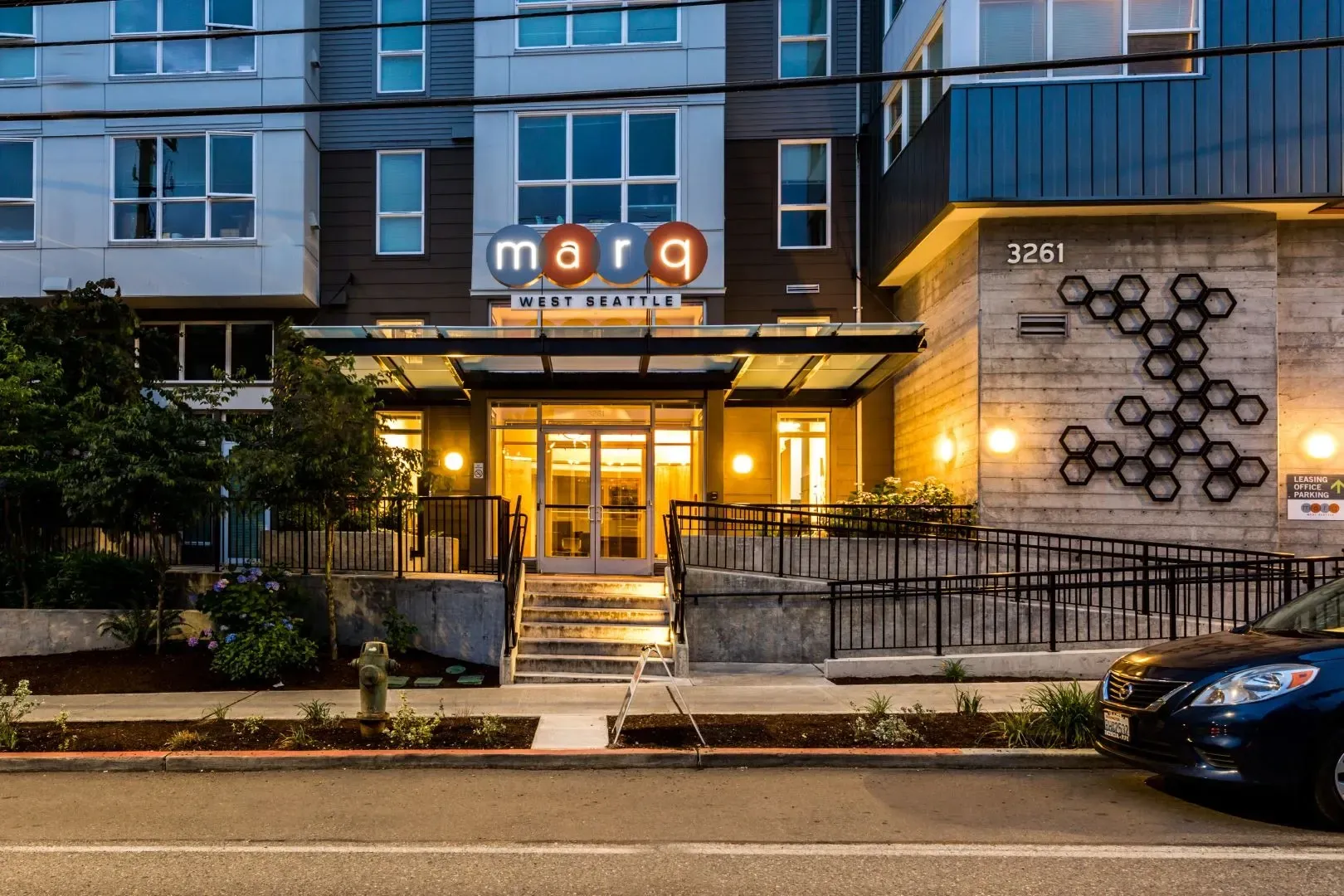 Marq West Seattle building entrance with illuminated lobby and decorative honeycomb wall art.