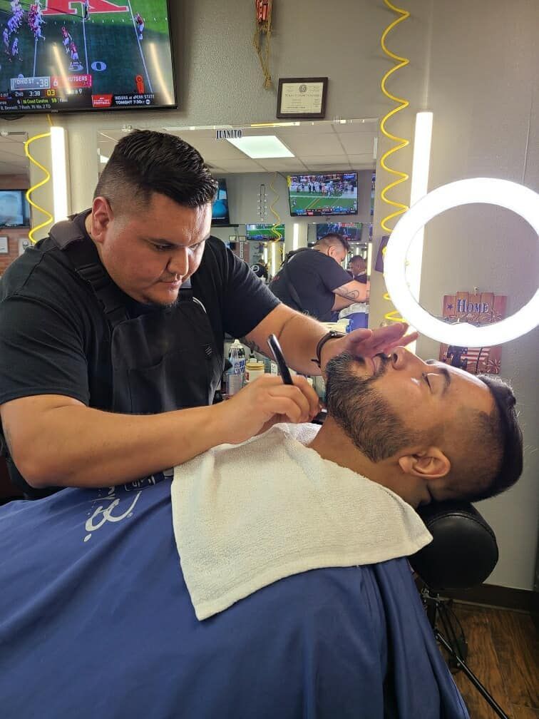 A man is getting his beard shaved by a barber in a barber shop.
