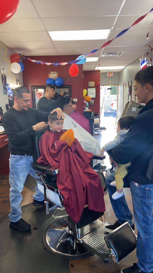 A group of people are getting their hair cut at a barber shop.