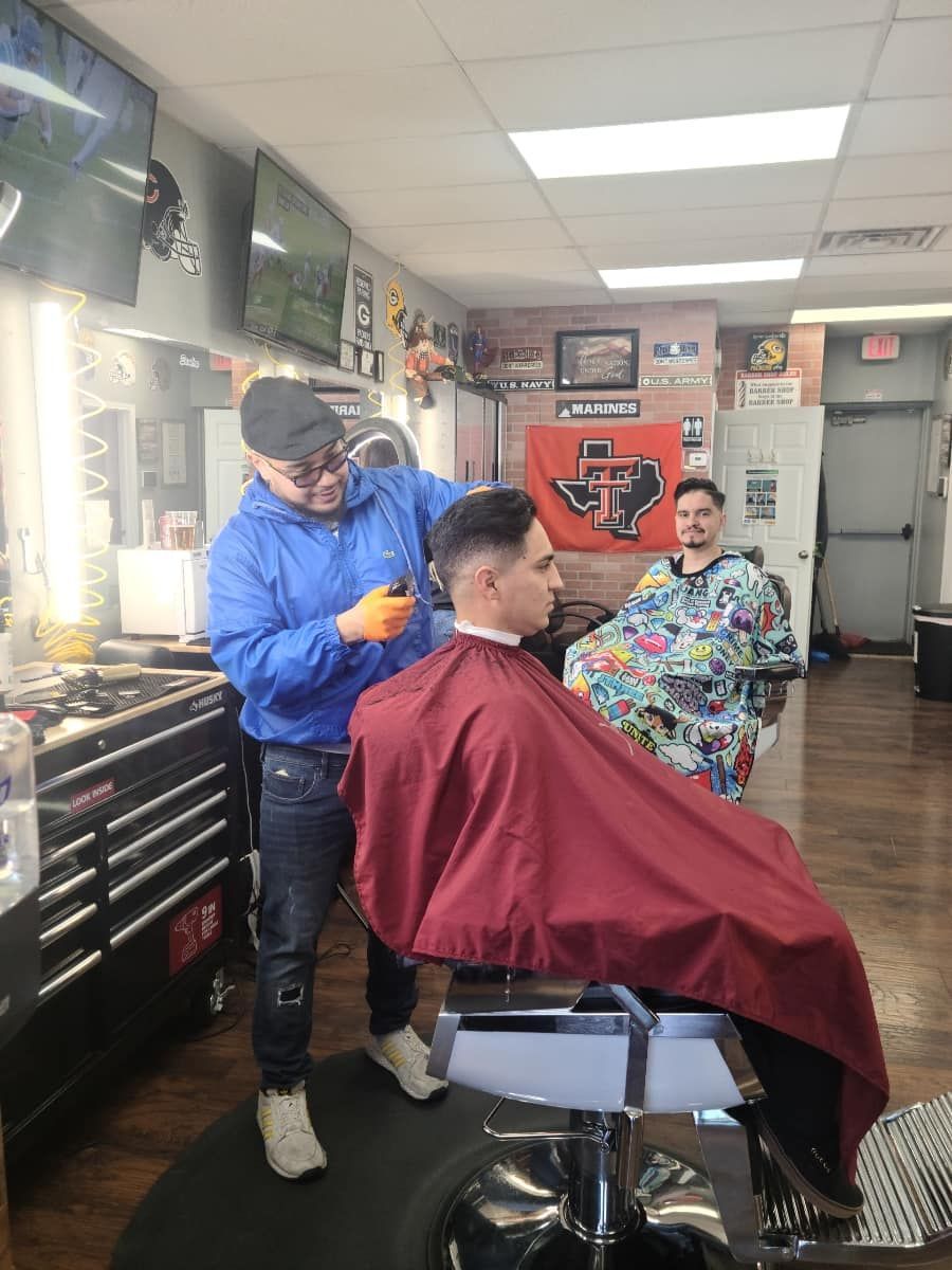 A man is getting his hair cut by a barber in a barber shop.