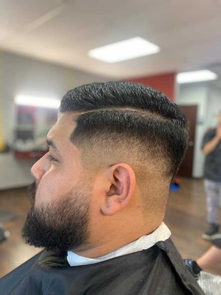 A man with a beard is getting his hair cut at a barber shop.