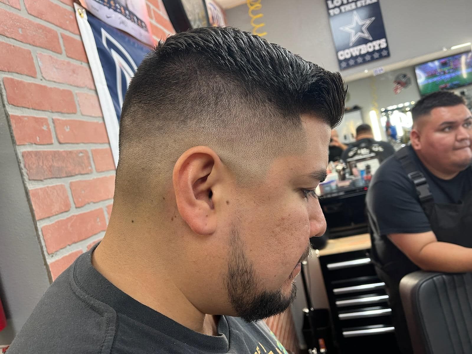 A man with a beard is getting his hair cut at a barber shop.