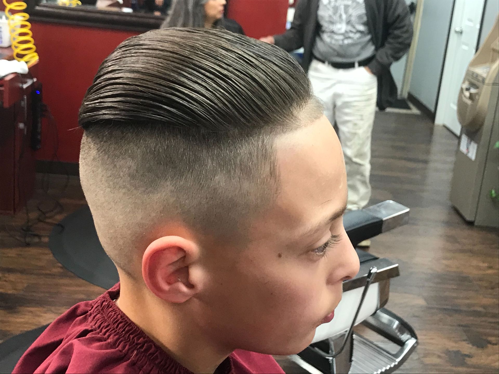 A young boy is getting his hair cut at a barber shop.