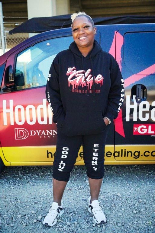 A woman standing in front of a van that says hood
