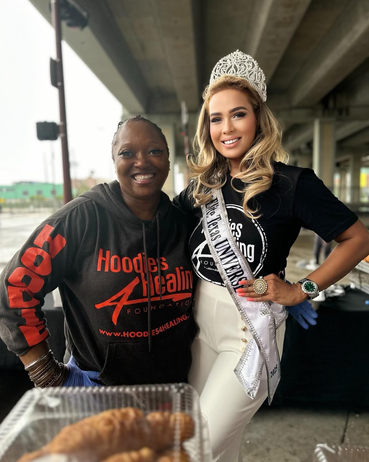 Two women are posing for a picture and one of them is wearing a crown.