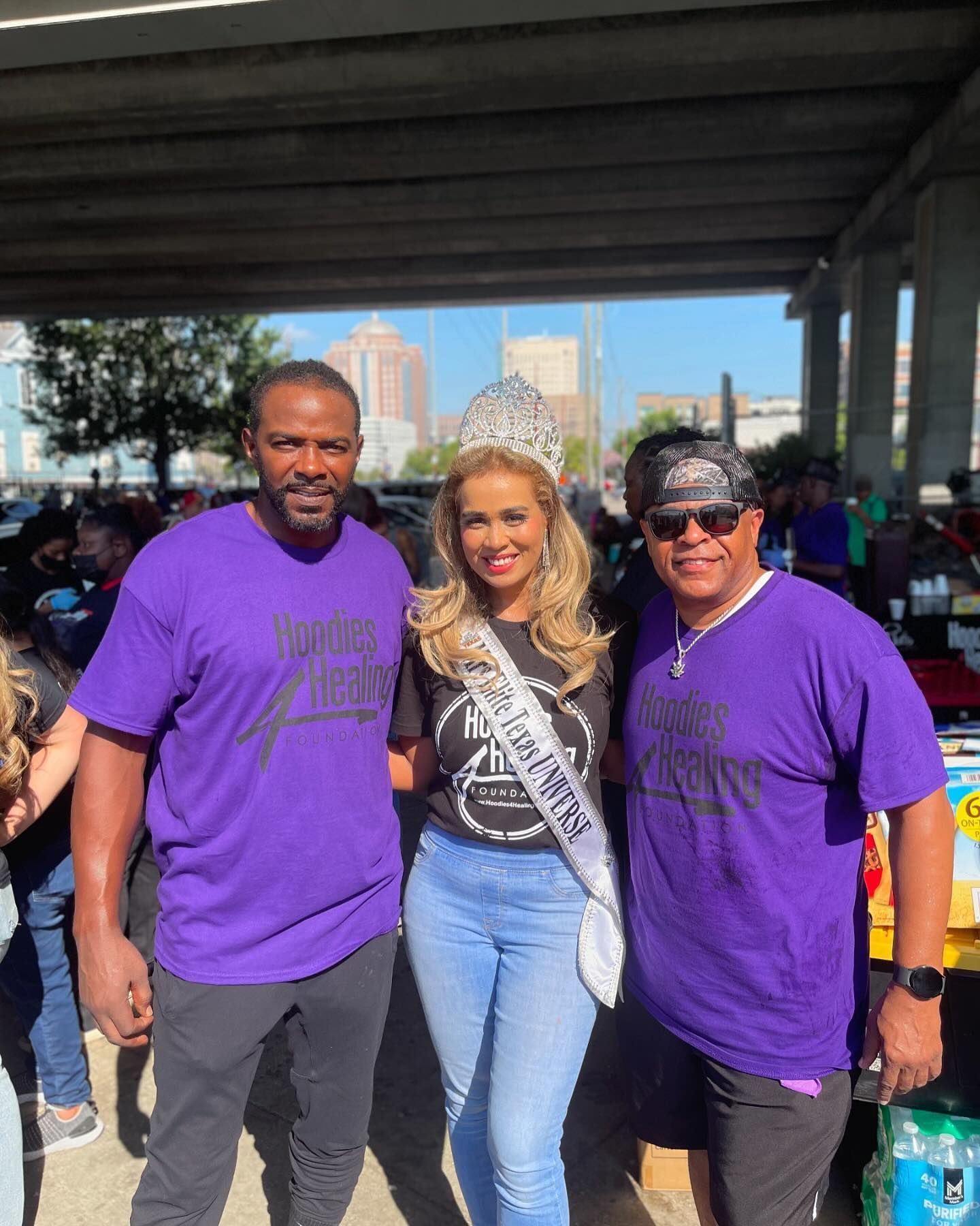 A woman wearing a crown is posing for a picture with two men.