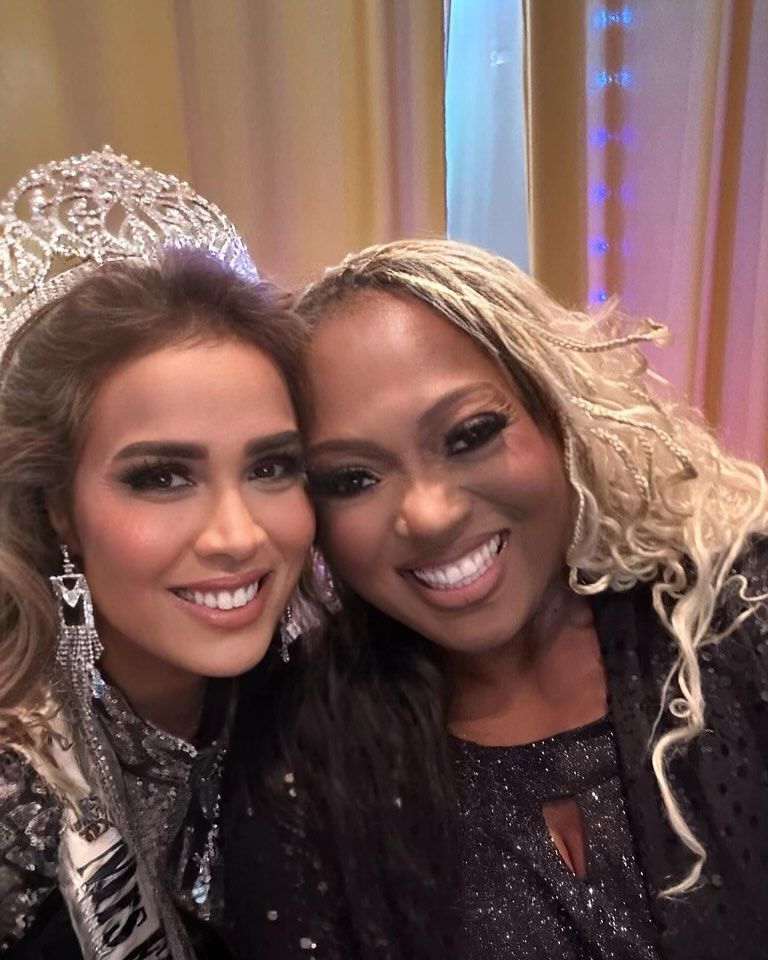 Two women posing for a picture with one wearing a miss universe crown