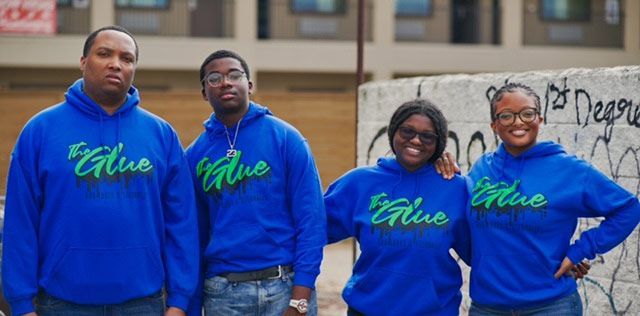 A group of people wearing blue hoodies are posing for a picture.