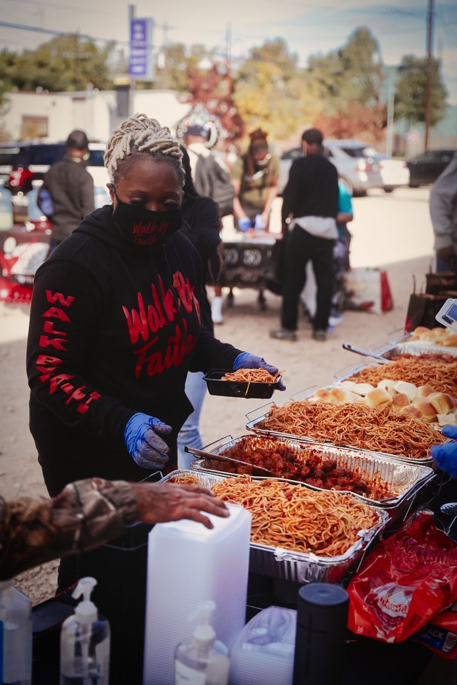 A woman wearing a mask is serving food at a table.