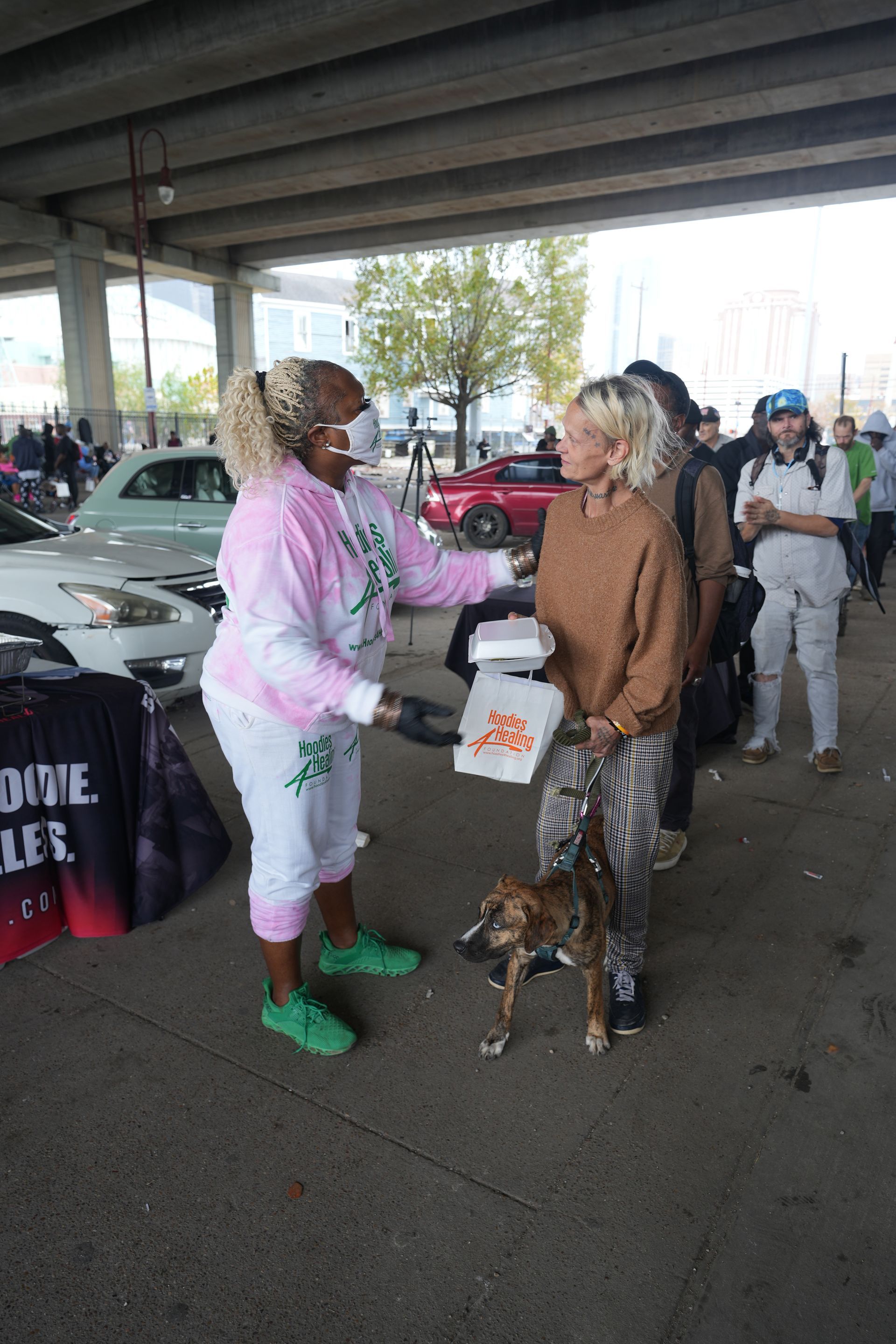 A woman is talking to a woman and a dog in a parking lot.