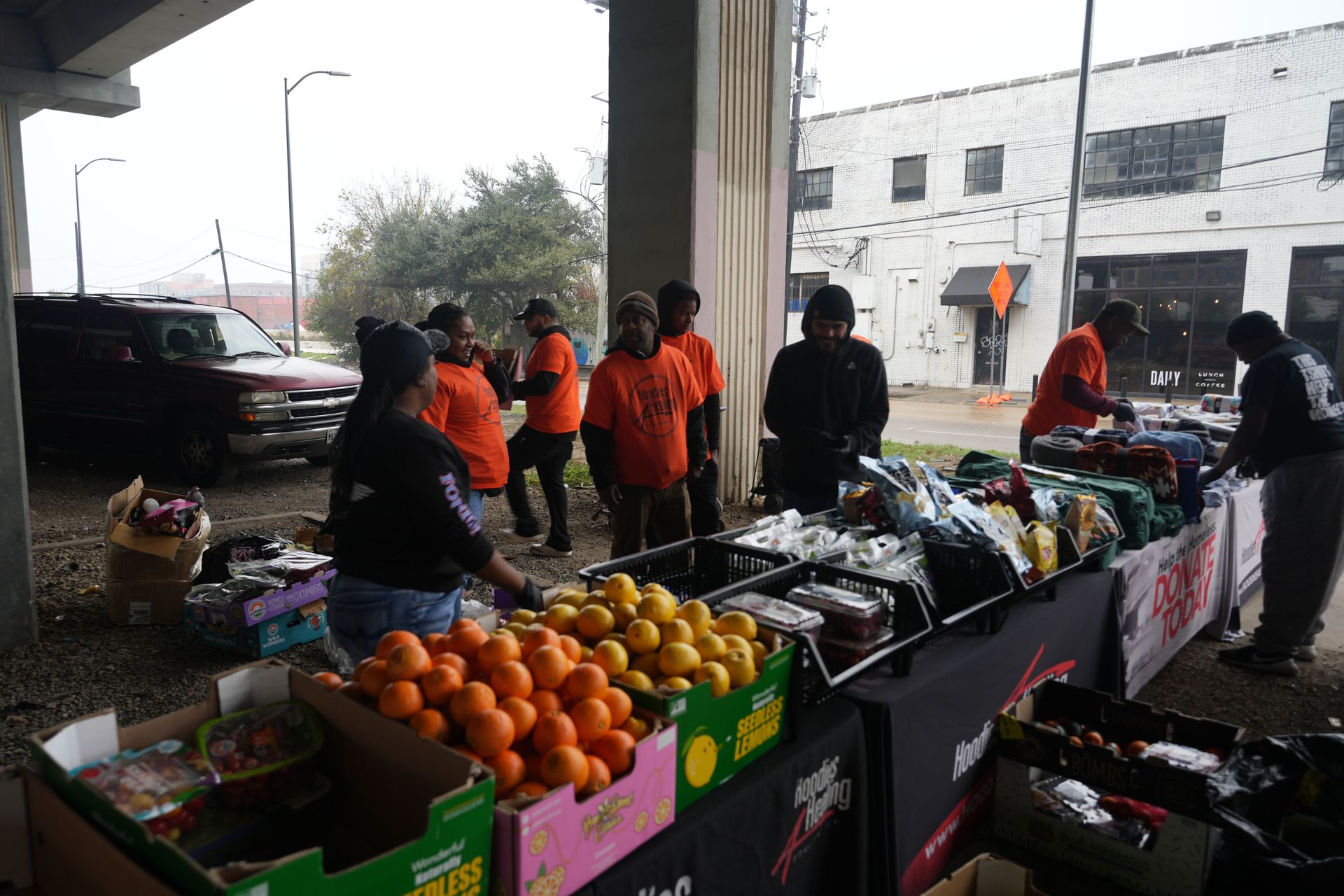A group of people are standing around a table full of fruits and vegetables.