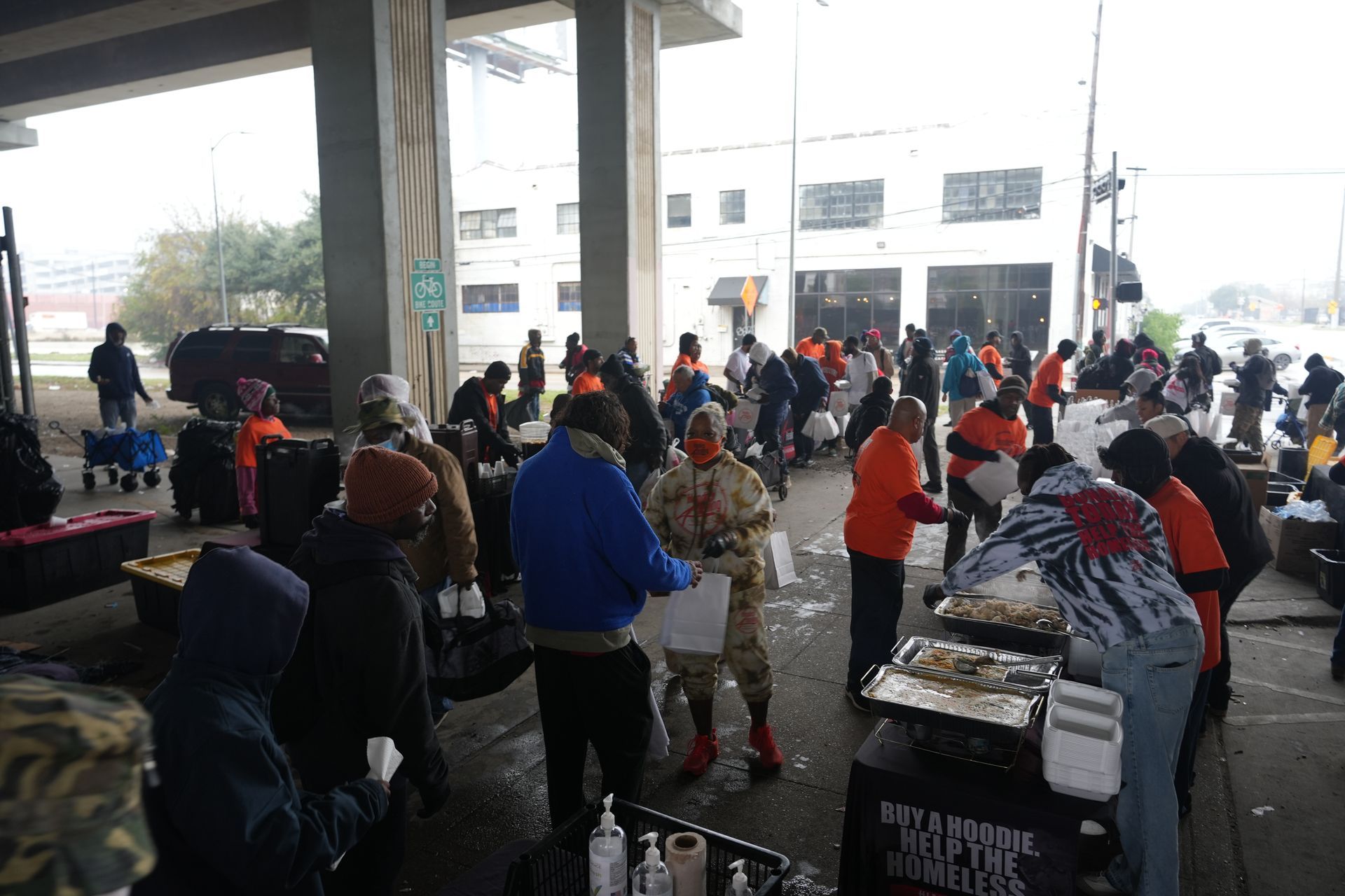 A group of people are standing around a table under a bridge.