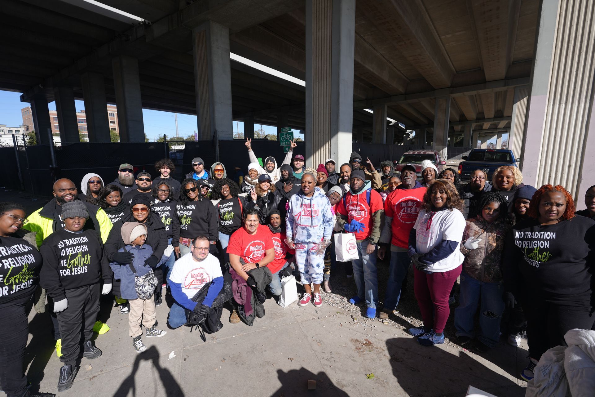 A group of people are standing around a table under a bridge.