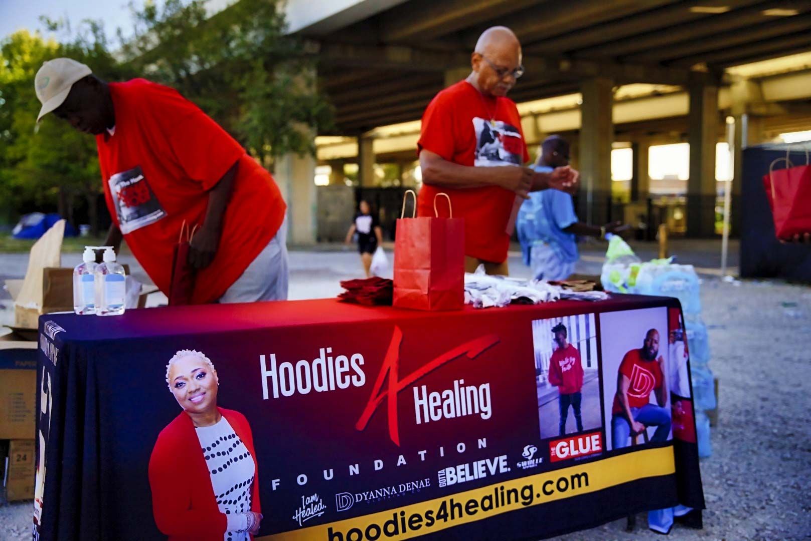 Two men standing around a table that says hoodies healing