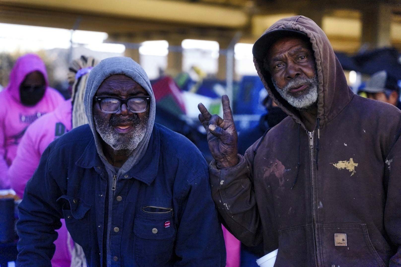 Two men are standing next to each other and one is giving a peace sign.