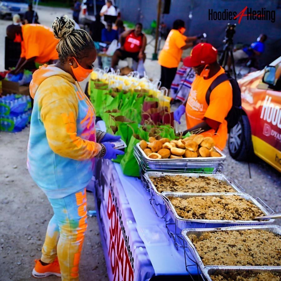 A woman wearing a mask is standing in front of a table full of food