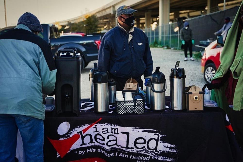 A man stands behind a table that says i am healed