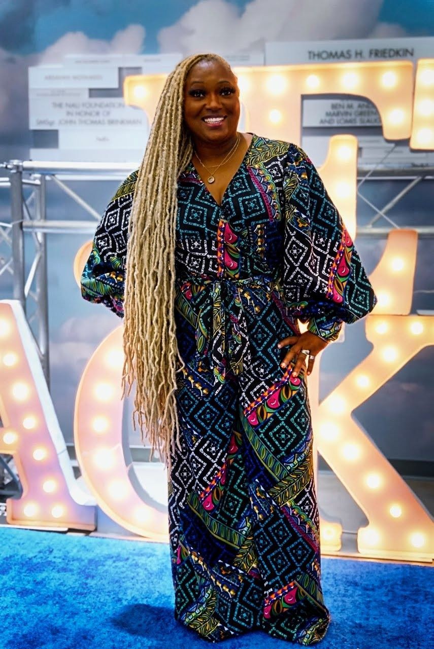 A woman in a long dress is standing on a blue carpet.