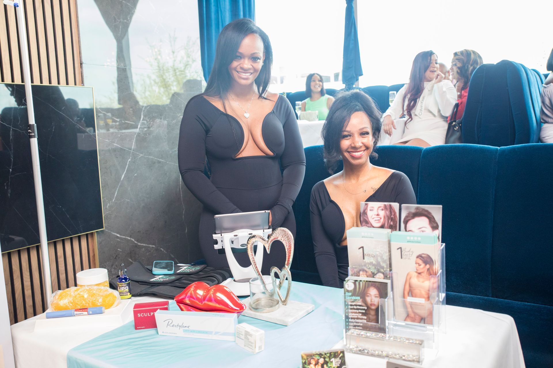 Two women are standing next to each other in front of a table.