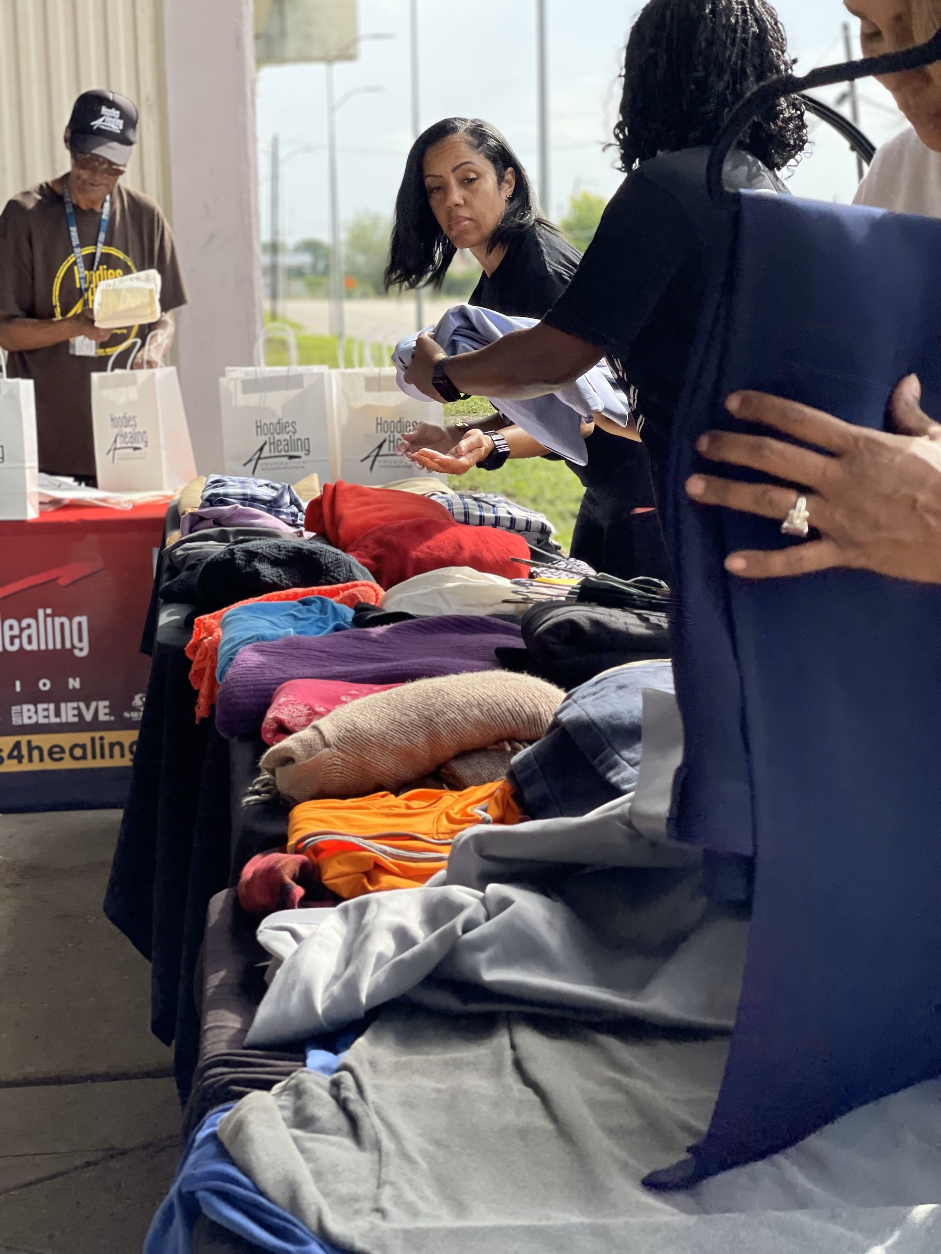 A group of people are standing around a table full of clothes.