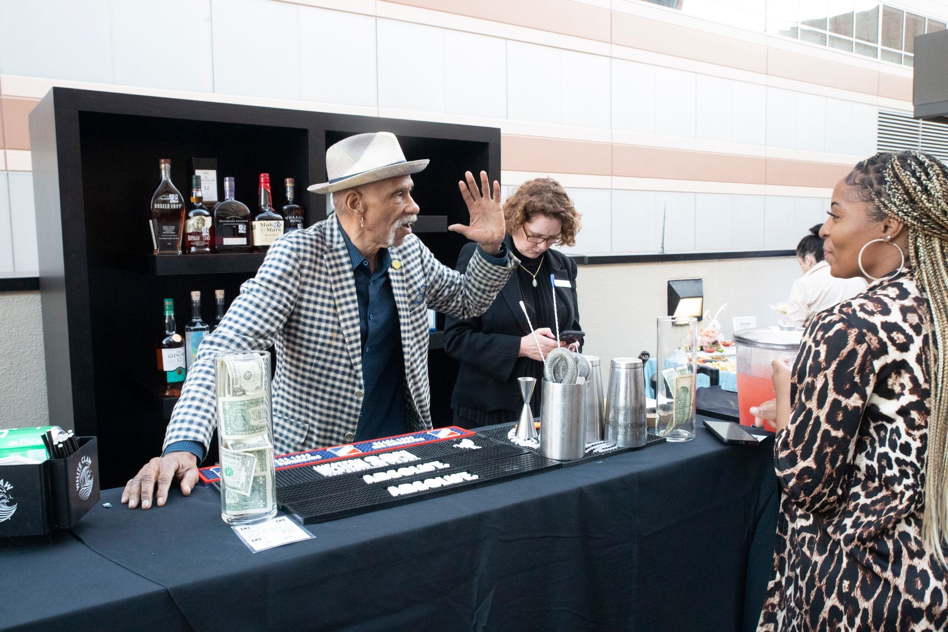A man in a hat is standing behind a bar talking to a woman.