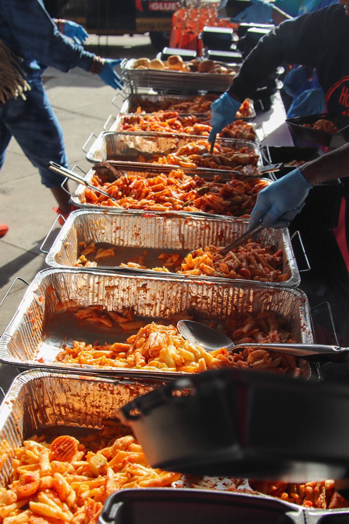 A group of people are serving food at a buffet table.