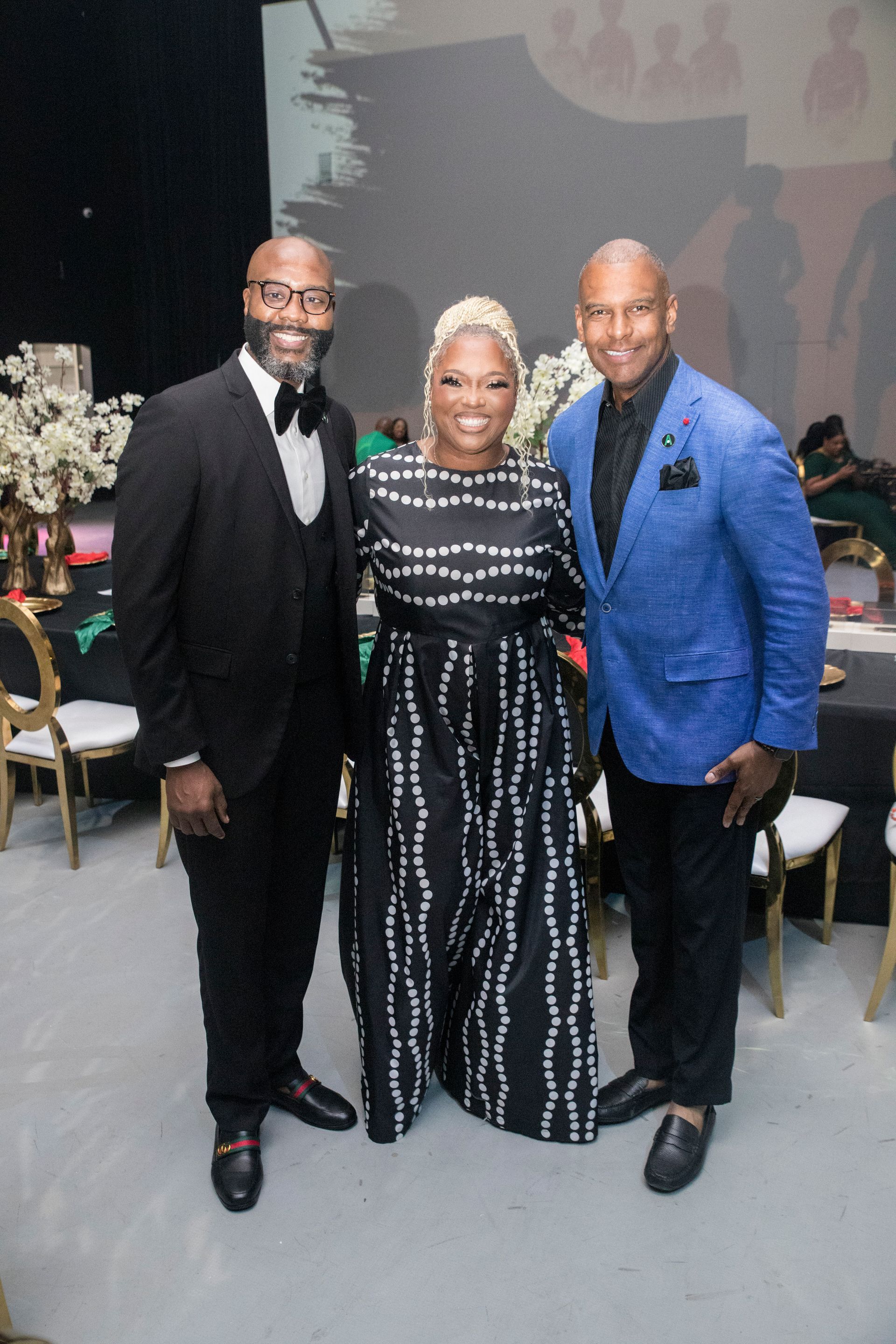 Two men and a woman are posing for a picture at a party.