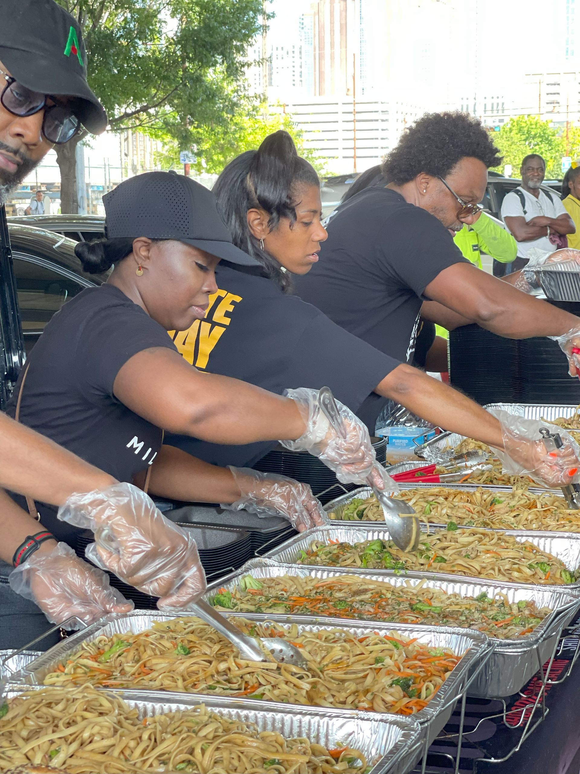 A group of people are standing around a table serving food.