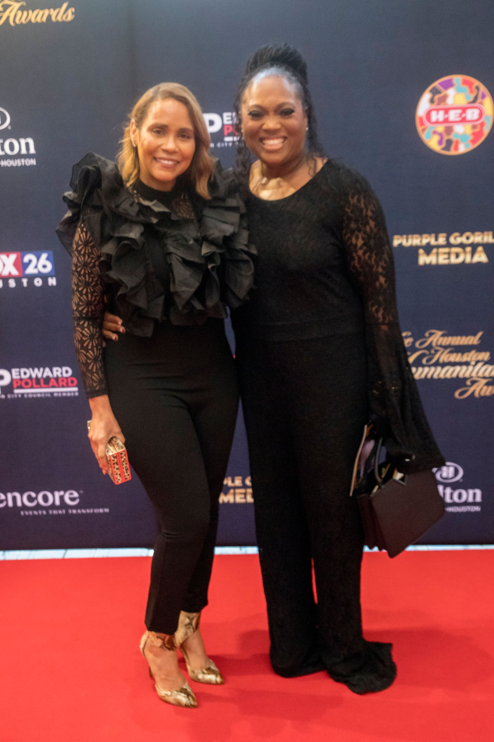 Two women are posing for a picture on a red carpet.