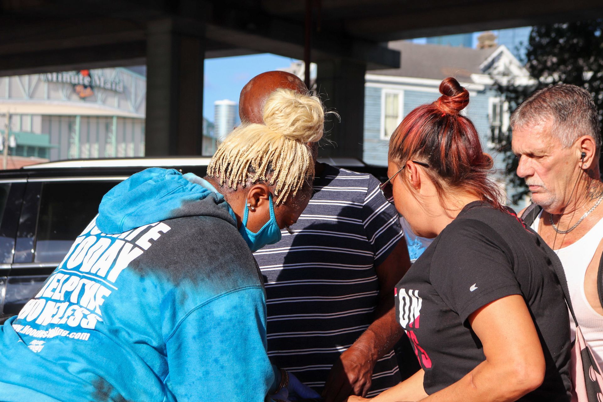A group of people are standing around a car talking to each other.