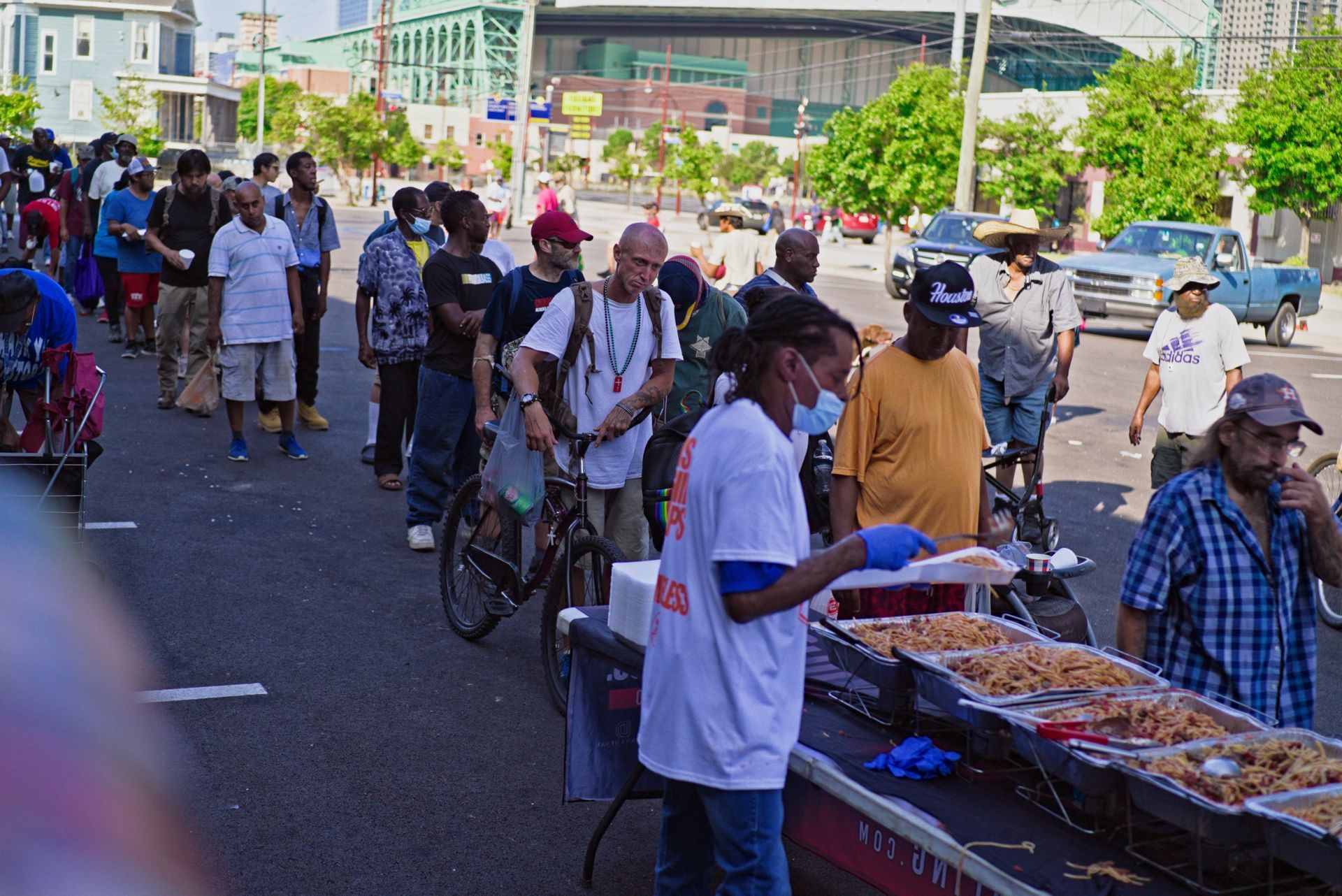 A group of people are standing in line to get food on the street.