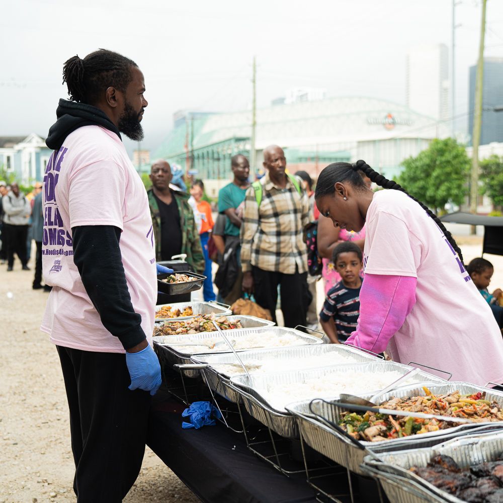A man in a pink shirt is standing next to a woman in a pink shirt serving food.