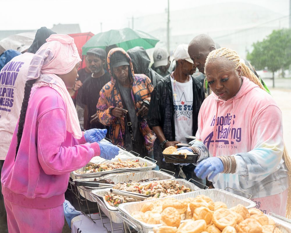 A woman in a pink shirt is serving food to a group of people.