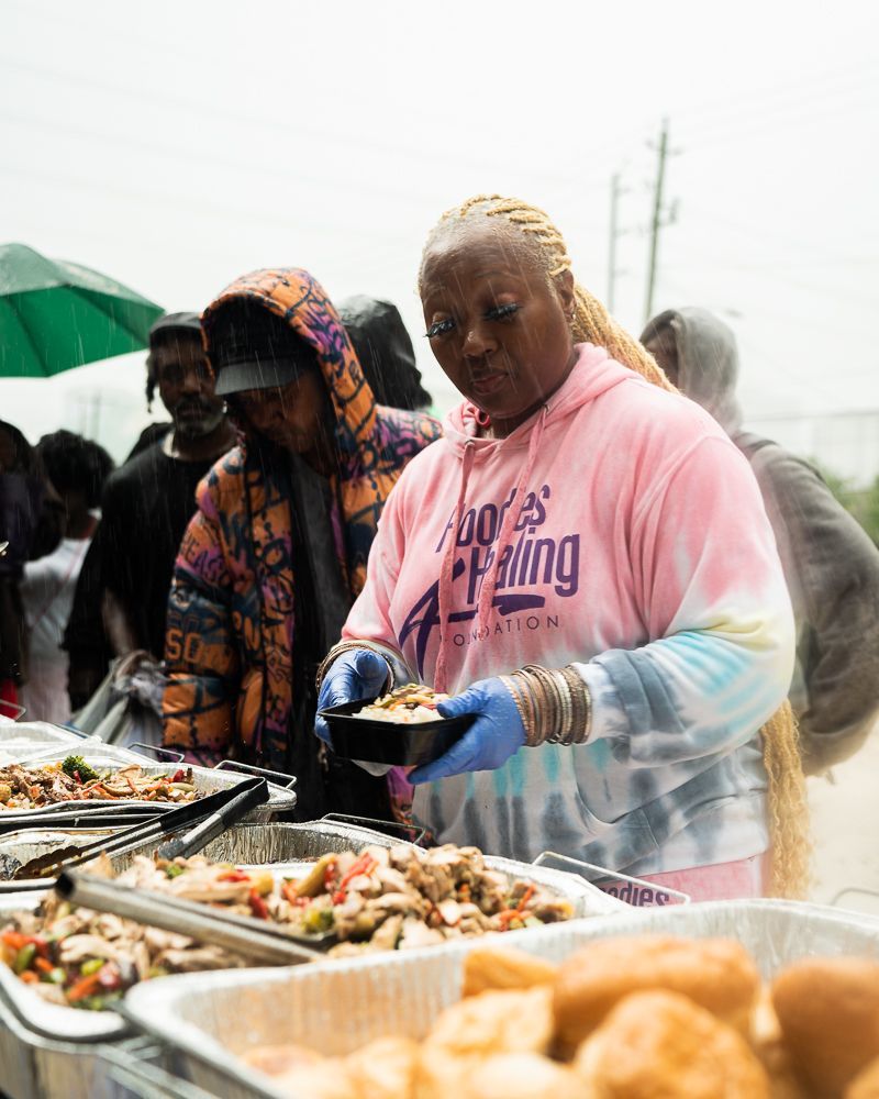 A woman in a pink shirt is serving food to a group of people.
