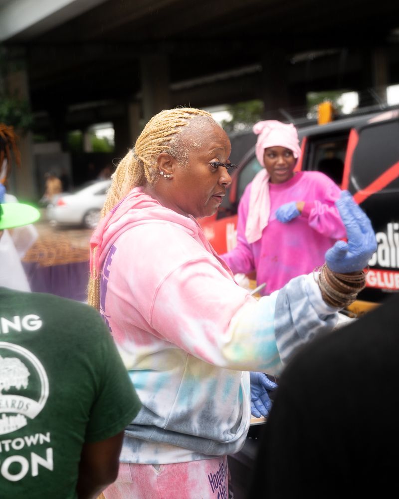 A woman wearing a tie dye hoodie is standing next to a man wearing a green shirt that says town on it