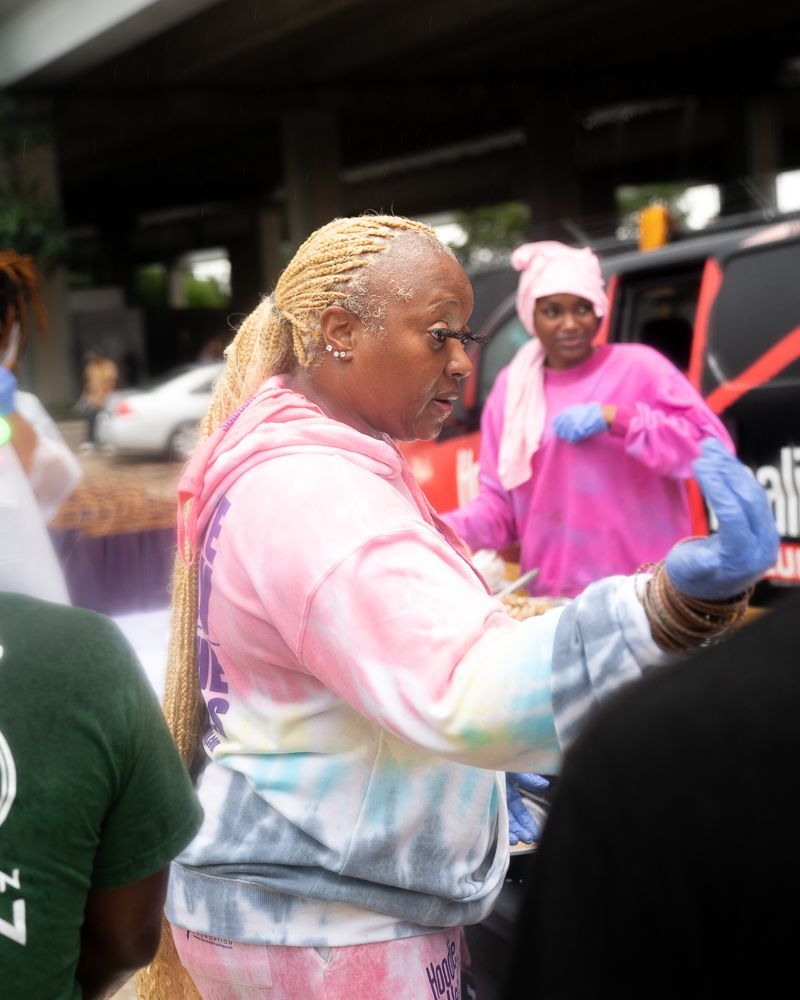 A woman in a pink tie dye sweatshirt is standing in a crowd of people.