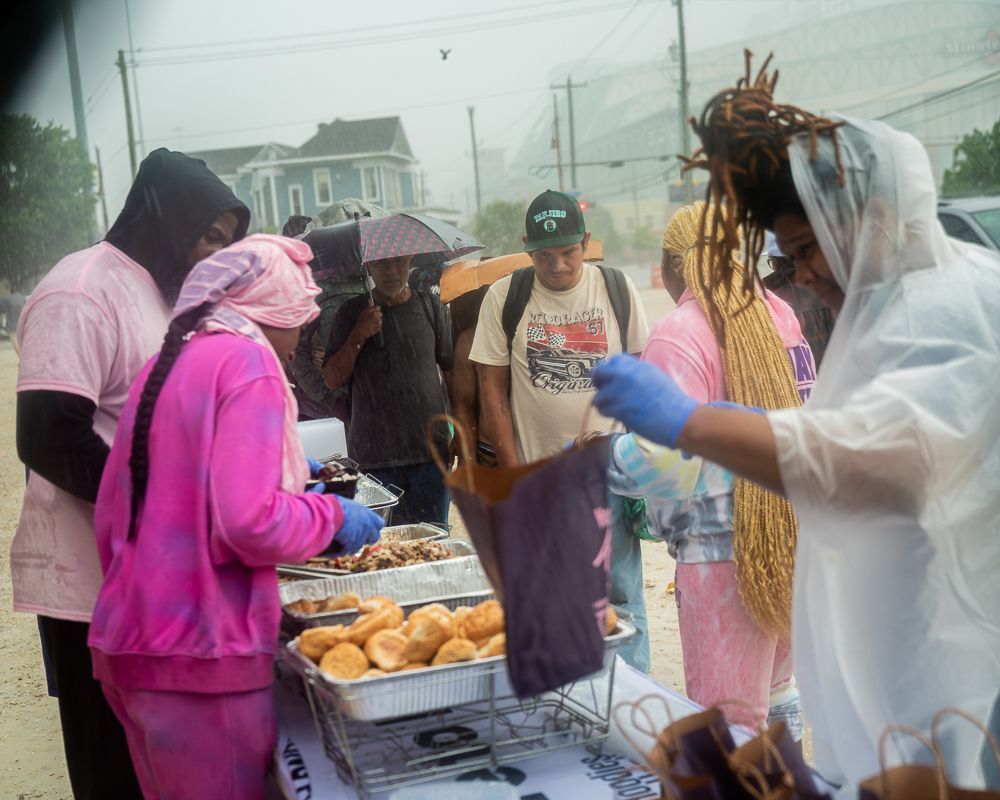 A group of people are standing around a table in the rain.