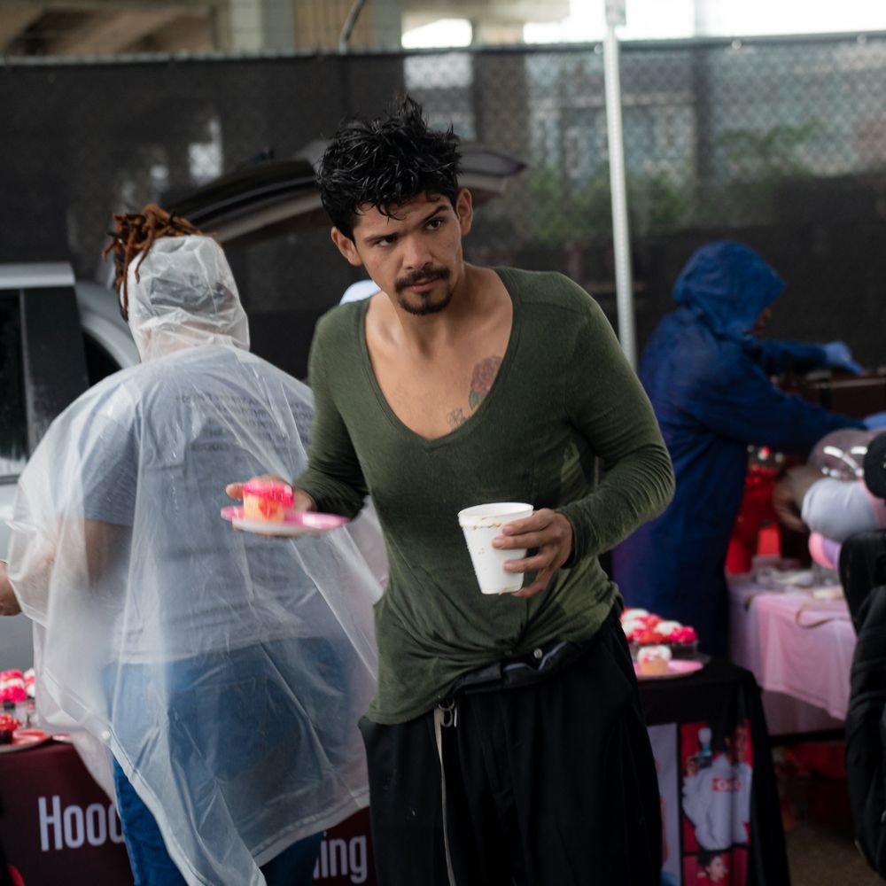 A man in a green shirt is holding a cup of coffee