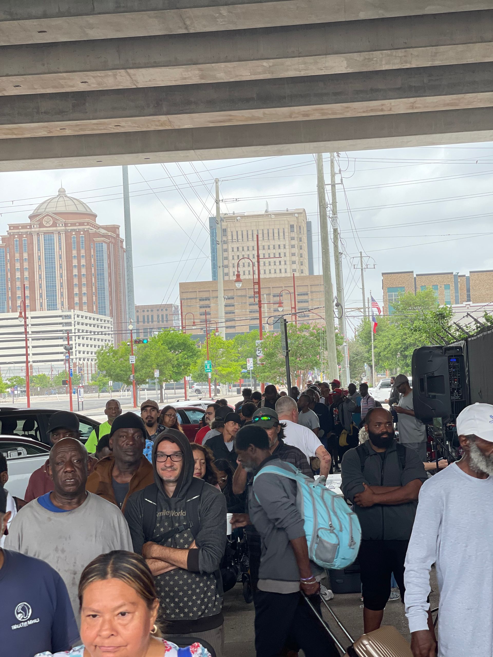A large group of people are standing under a bridge.
