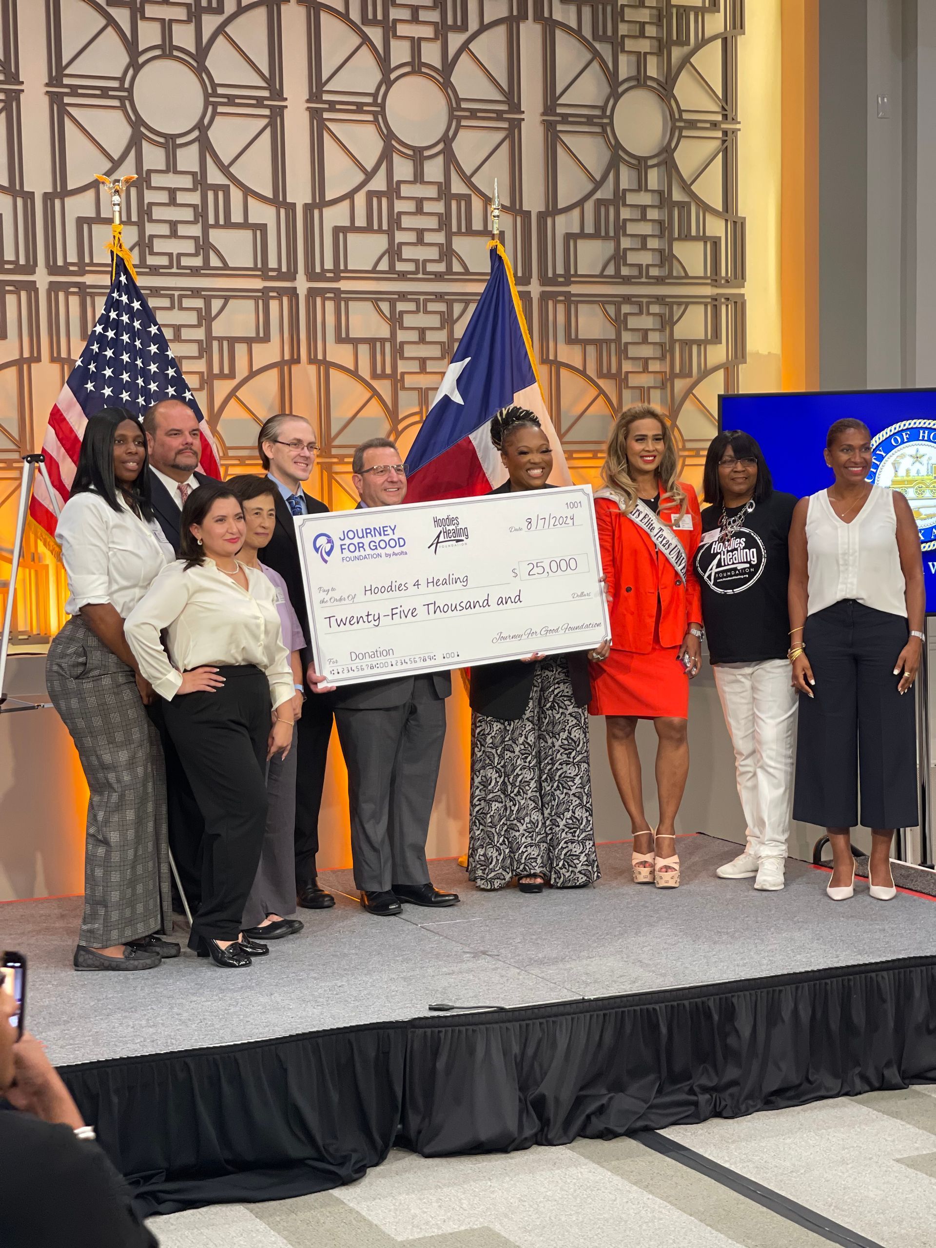 A group of people standing on a stage holding a large check