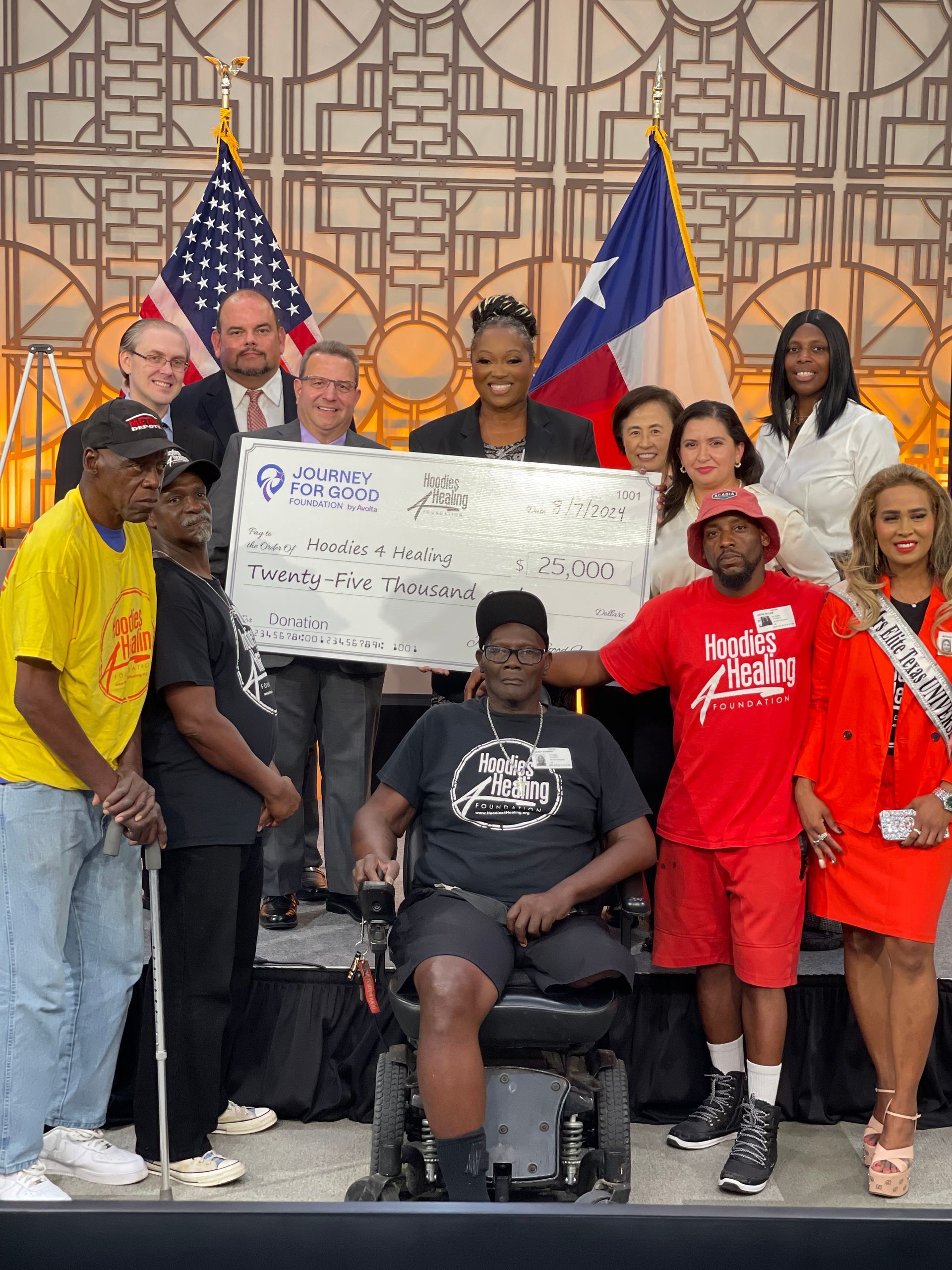 A group of people standing around a man in a wheelchair holding a check.