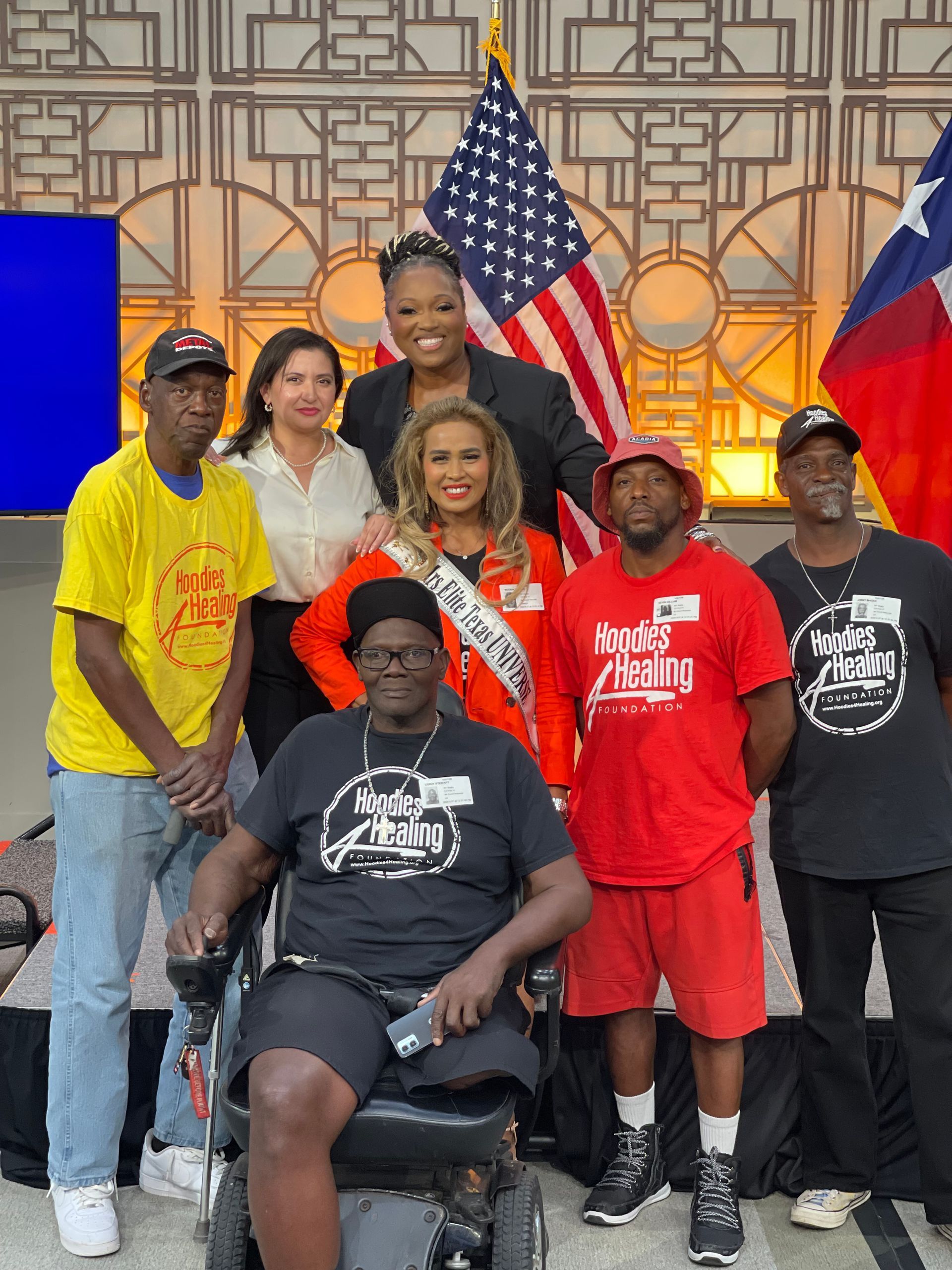 A group of people are posing for a picture with a woman in a wheelchair.