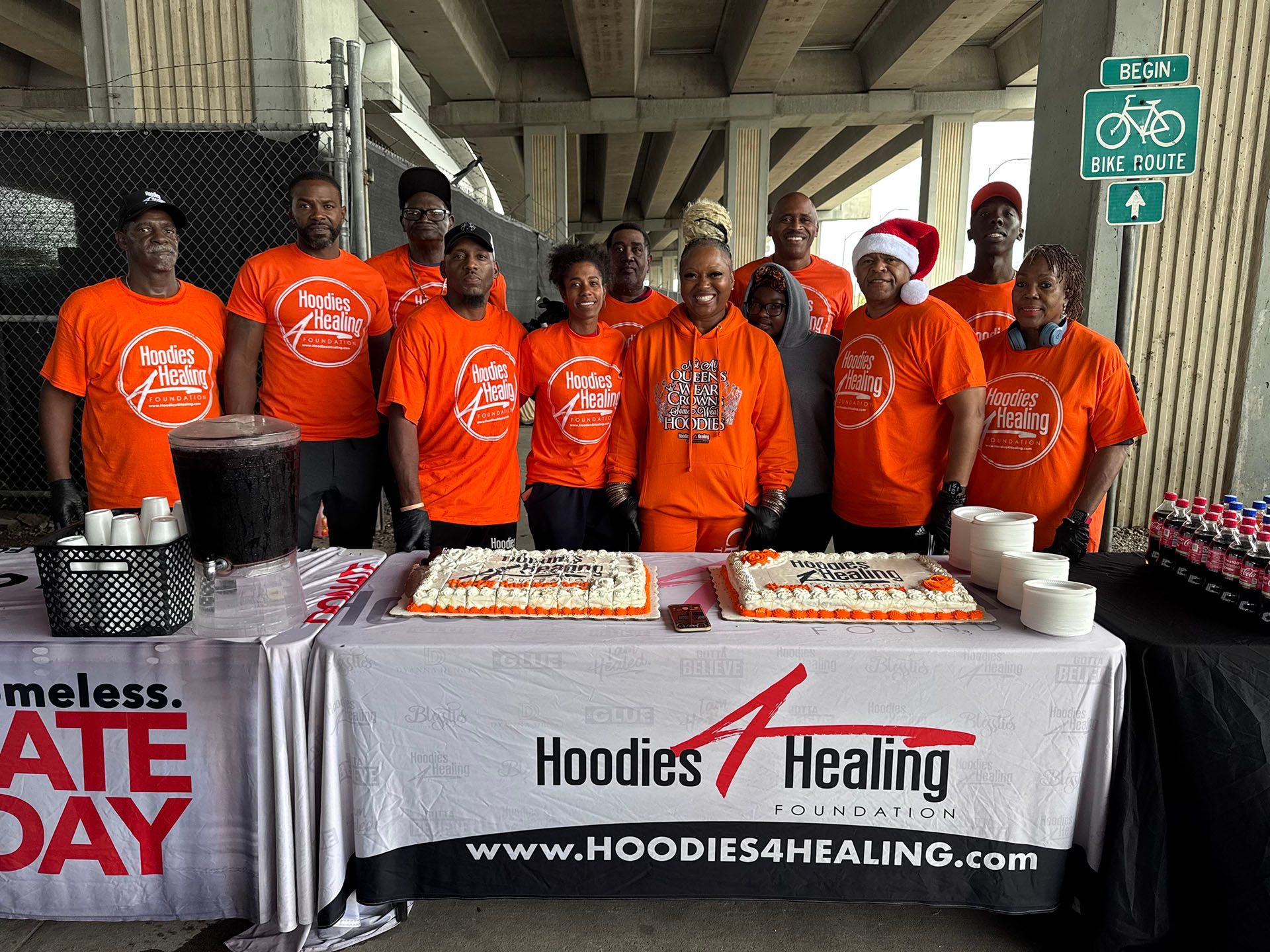 A group of people standing around a table with a cake on it.