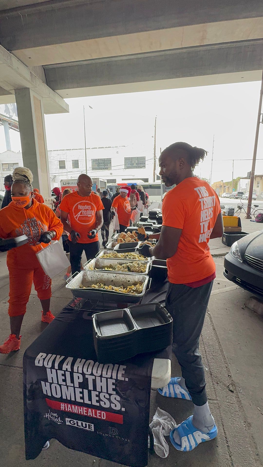 A group of people are standing around a table with food on it.